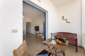 A dining area with a table set for two, a wooden bench, and a fruit plate. - Famara Views III by Escape Home (Famara)