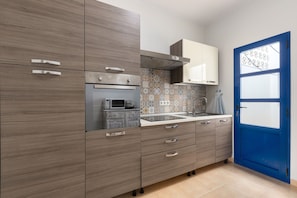 A modern kitchen with grey cabinets, a stainless steel range, and a blue door. - Famara Views III by Escape Home (Famara)