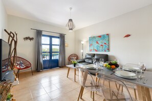 A modern living room with a dining area, a sofa, a TV, and a large window with curtains. - Famara Views III by Escape Home (Famara)