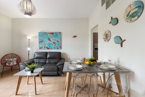 A dining area with a table set for four, a sofa, and a red chair. - Famara Views III by Escape Home (Famara)