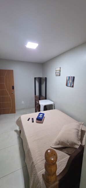 A bedroom with a bed, a wooden door, a white table, and a mirror. - Hangar House Hostel (Belém)