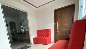 A modern living room with a red sofa, a wooden door, and a glass partition. - Hangar House Hostel (Belém)