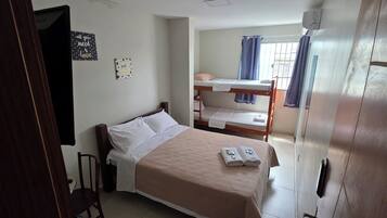 Une chambre avec un lit simple, un lit superposé, une chaise et une armoire.