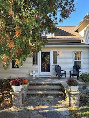 Una casa con una escalera de piedra que lleva a la puerta principal, dos sillas Adirondack y un buzón con el número 5051.