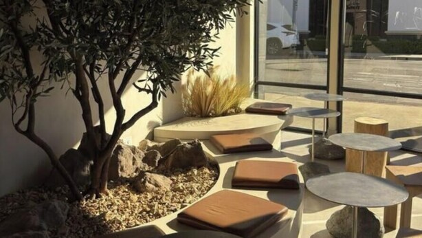 An outdoor seating area with round tables and cushioned benches, surrounded by rocks and plants. - SGV Quadruple Room + Explore Disney & Downtown LA (Alhambra)
