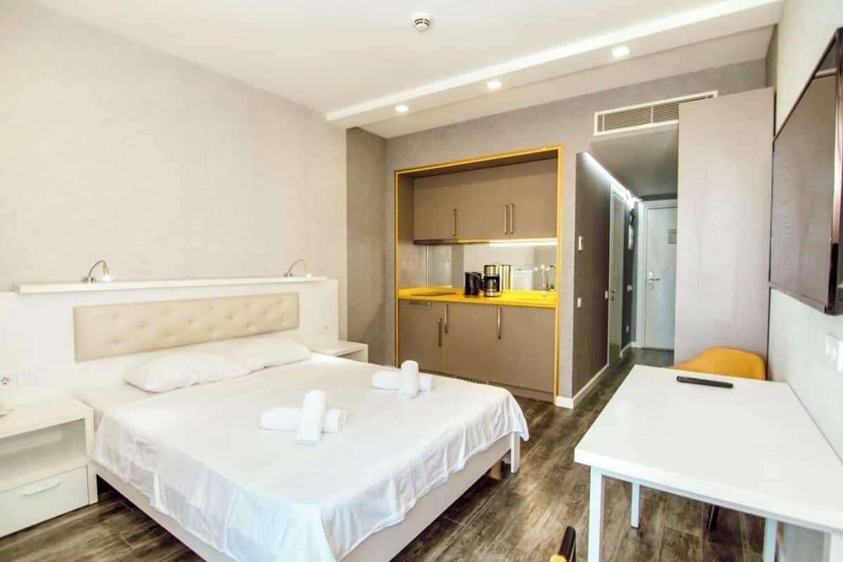 A hotel room with a bed, a desk, and a kitchenette.