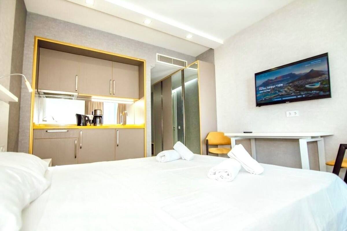 A hotel room with a bed, a TV, a desk, and a wardrobe.