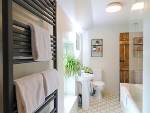 A modern bathroom with a black towel rack, white sink, toilet, and a glass shower enclosure.