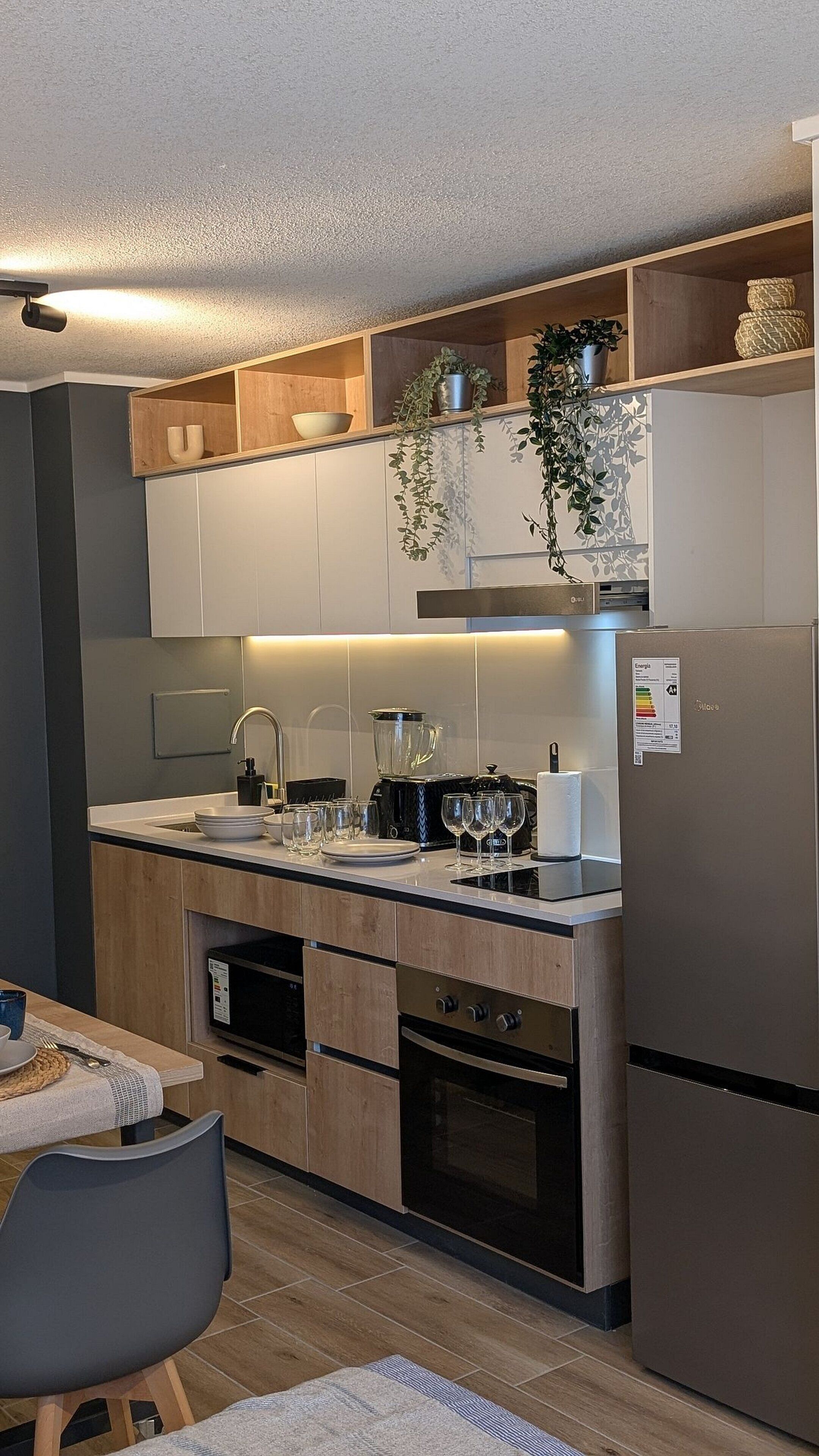 Una cucina moderna con mobili in legno, forno a incasso, frigorifero e zona pranzo con tavolo e sedie.