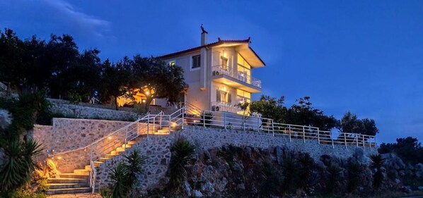 A two-story house with a stone staircase leading to a balcony.