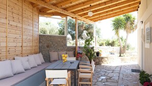 An outdoor patio with a wooden table, chairs, and a built-in bench. - ADRIANA'S House KARDAMYLI PROSILIO (Unknown)