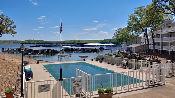 A swimming pool with a lifeguard tower, a flag, and a sign indicating pool rules.