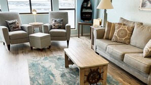 A living room with a sofa, armchairs, a coffee table, and a rug.