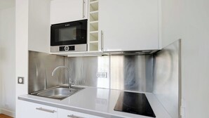 A modern kitchen with white cabinets, stainless steel appliances, and a built-in microwave. - Cosy Apartment -1br-2p- Suresnes (Suresnes)