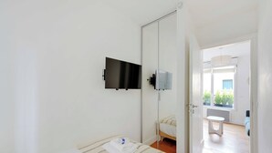A hotel room with a bed, a TV mounted on the wall, and a view of the outside balcony. - Cosy Apartment -1br-2p- Suresnes (Suresnes)