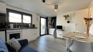 A modern kitchen with a microwave, stove, and sink, a dining area with a table and chairs, and a living room with a sofa.