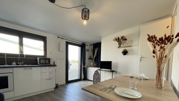 A modern kitchen with white cabinets, a microwave, and a dining area with a wooden table and chairs.