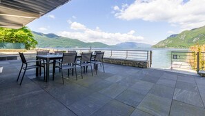 An outdoor patio with a table and chairs, a stone wall, and a view of a lake and mountains. - LE ST-INN - BRISON SAINT INNOCENT (BRISON SAINT INNOCENT)
