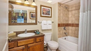 A bathroom with a sink, mirror, toilet, and bathtub.