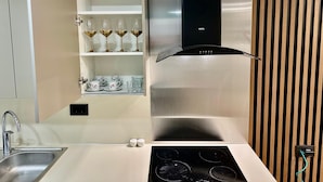 Uma cozinha moderna com pia de aço inoxidável, forno embutido e coifa.