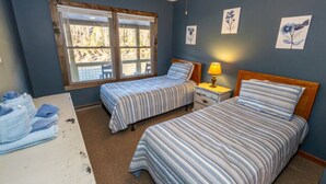 A bedroom with two beds, a window, and a bedside table with a lamp. - Twin Falls Cabin Top Duplex (Spruce Pine)