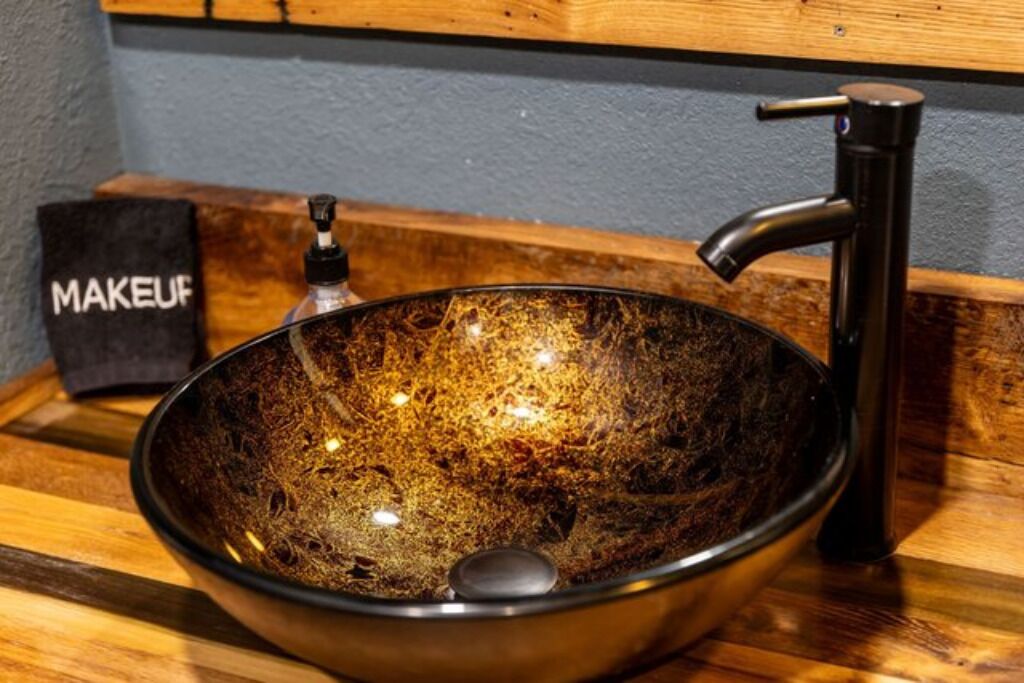 A dark, textured bowl sink with a modern faucet, placed on a wooden countertop.