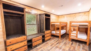Una habitación de madera con literas, cajones integrados y una ventana.