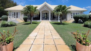 A two-story house with a central entrance, a covered patio, and a well-maintained lawn.