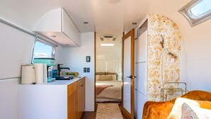 Ein kompaktes Wohnmobil-Interieur mit Küchenzeile, einem Bett und einer kleinen Sitzecke.