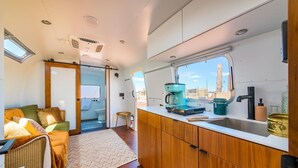Ein kompaktes Wohnmobil-Interieur mit Küchenzeile, einer kleinen Sitzecke und Blick durch ein Fenster.