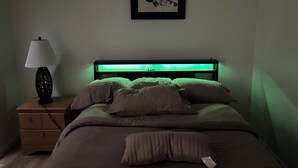 Une chambre à coucher avec un lit, une table de chevet avec une lampe et un tableau encadré au mur.