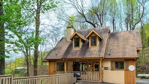 A lodge with a stone facade, wooden deck, and a chimney.