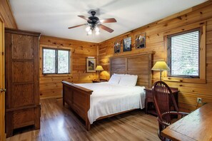 A wooden cabin bedroom with a bed, two bedside lamps, a chair, and a desk. - Smoky Mountain Escape | Amazing Views & Hot Tub (Gatlinburg)