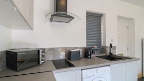 Una cocina compacta equipada con microondas, tostadora, hervidor y lavadora.