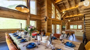 A wooden dining table set with blue plates, wine glasses, and a vase of flowers. - CHALET DES FEES - BEAUFORT (BEAUFORT)