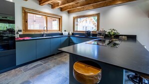 A modern kitchen with a large island, built-in appliances, and large windows. - CHALET DES FEES - BEAUFORT (BEAUFORT)