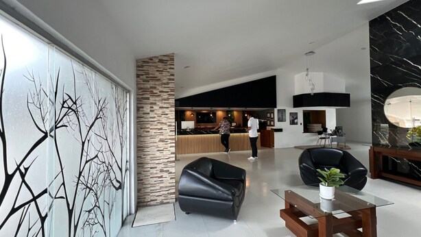 Un interior moderno con mostrador de recepción, un sofá de cuero negro y una zona de comedor.