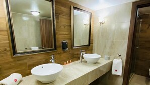Un baño moderno con dos lavamanos, paneles de pared de madera y un espejo grande.