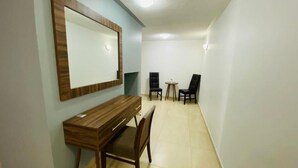 Una habitación pequeña y bien iluminada con un escritorio de madera, dos sillas y una mesa redonda.