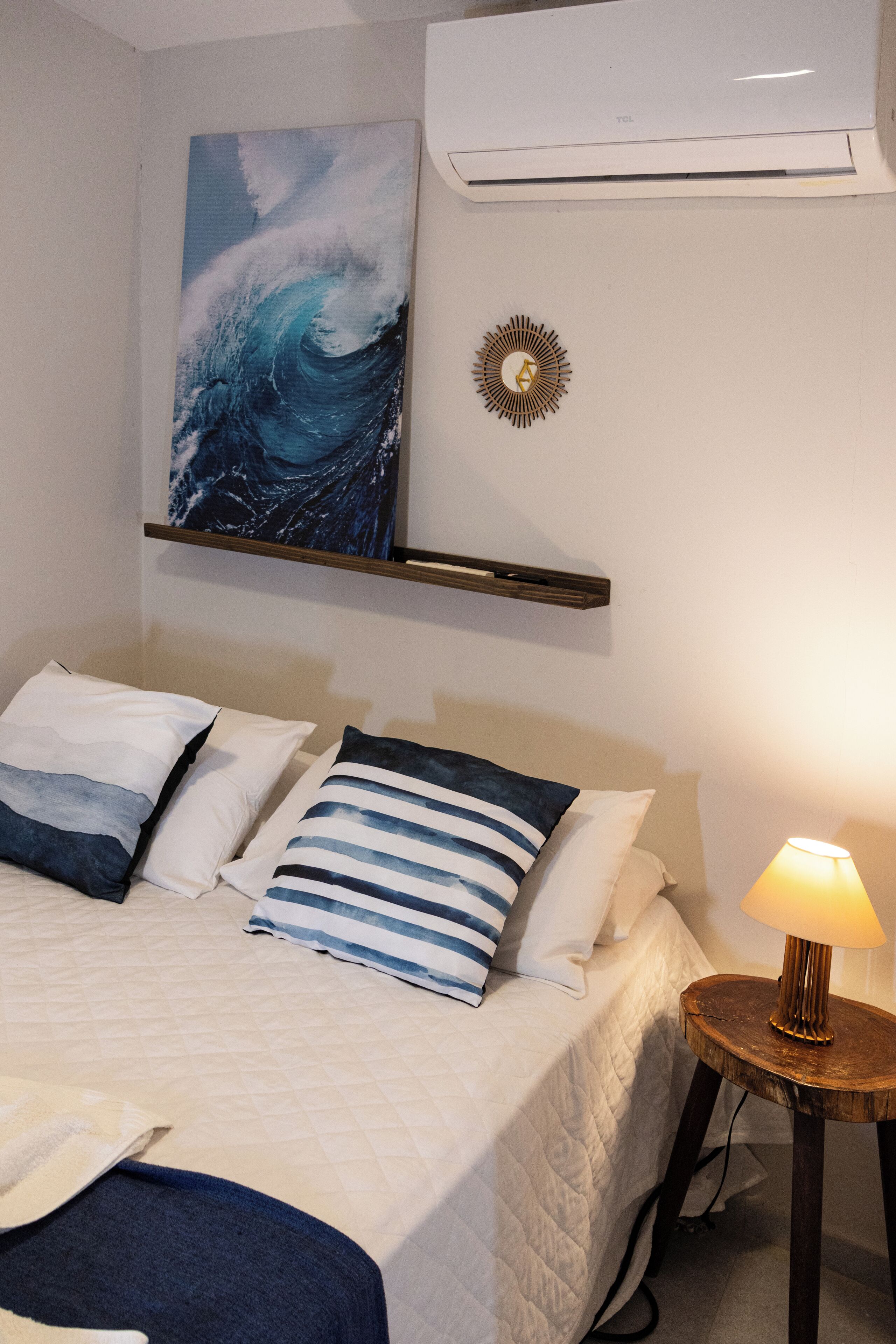 Ein Schlafzimmer mit einem Bett, Kissen, einer Wand-Klimaanlage, einem Wanddekor und einer Nachttischlampe.