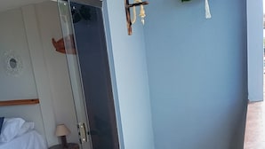 Quarto com cama, uma mesinha com luminária, uma cadeira de madeira e um vaso com planta.