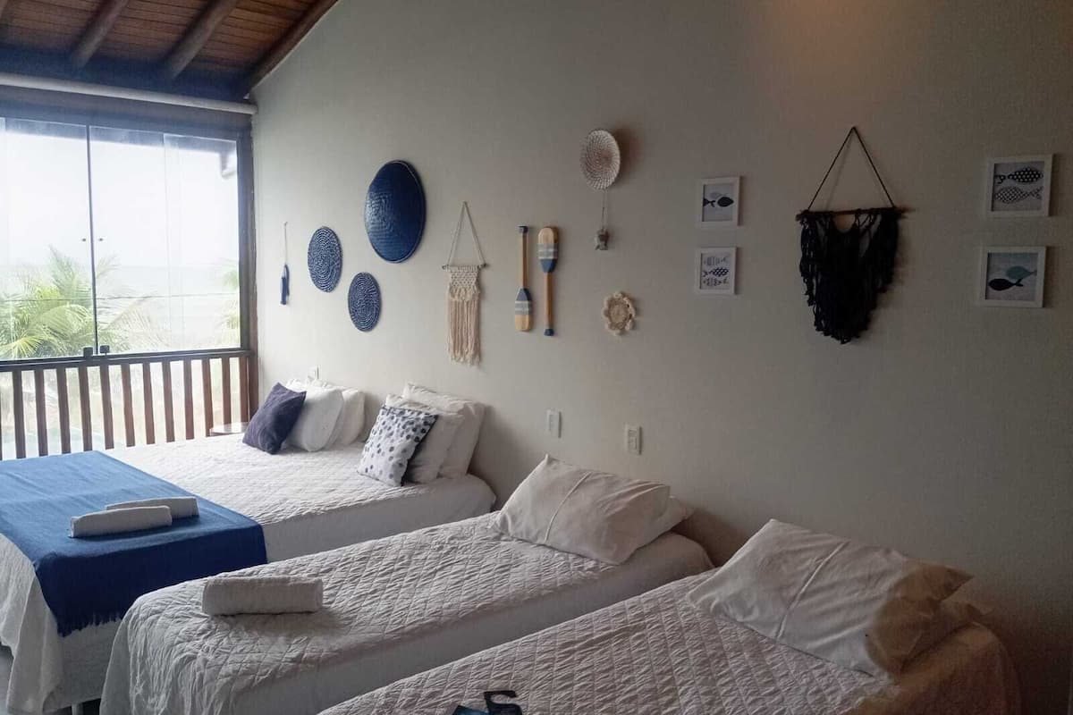 Ein Zimmer mit zwei Betten, einem Balkon und verschiedenen Wanddekorationen, darunter Teller und eine Wandweberei aus Fransen.