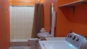 Une petite salle de bain compacte, équipée d’une douche, de toilettes et d’un lavabo.