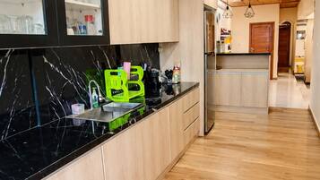Een moderne keuken met houten kastjes, een zwarte marmeren aanrecht en een rood tapijtbalkje.