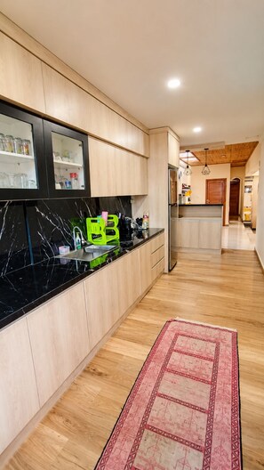 Een moderne keuken met houten kastjes, een zwarte marmeren aanrecht en een rood tapijtbalkje.