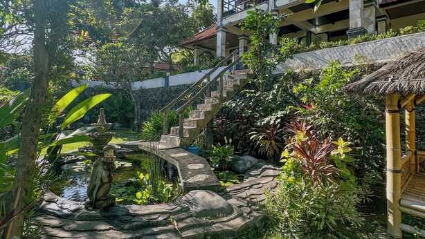 A garden with a stone fountain, a statue, and a staircase leading to a building with a balcony. - Charming 3-bedroom villa with WiFi, AC in the Air Sanih, The north of Bali (Bali)