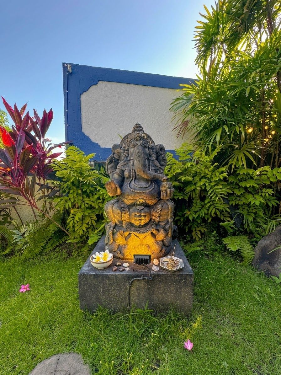 A statue of a deity in a garden setting with a clear sky.