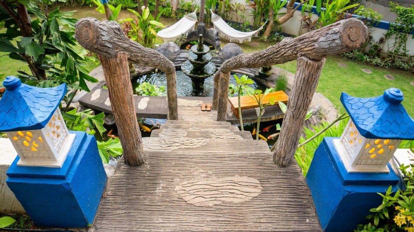 A wooden bridge with a patterned walkway leading to a pond with a fountain.