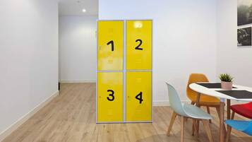 Un espacio de oficina moderno con suelo de madera, pared blanca y una mesa con sillas coloridas.