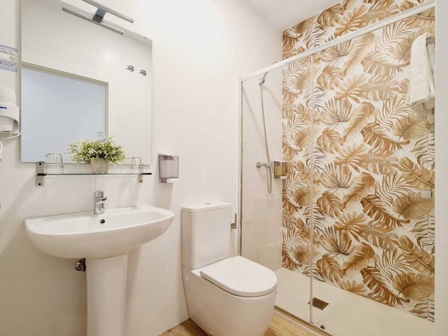 Un baño con lavamanos, inodoro y ducha blancos.